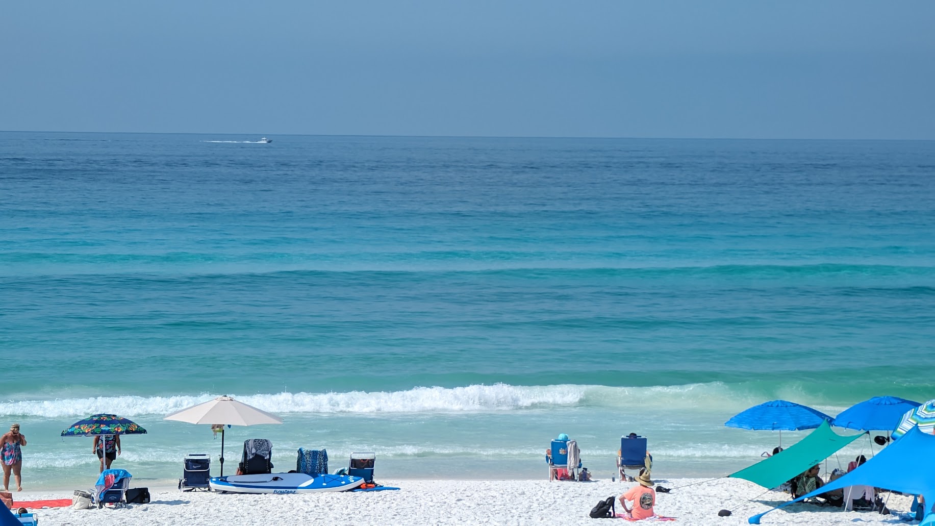 Empty white sand beach in Miramar Beach Florida with calm emerald Gulf water and natural dune vegetation under blue sky